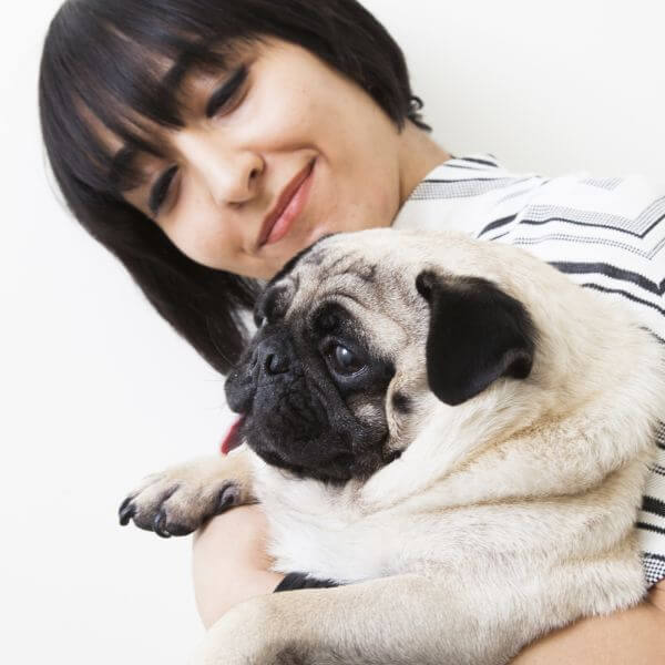 A lady holding a pug dog in hand